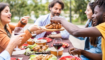Group of people sharing a meal outside and smiling