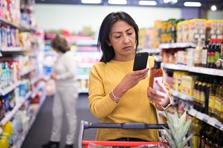 Woman scanning food label with phone in grocery store