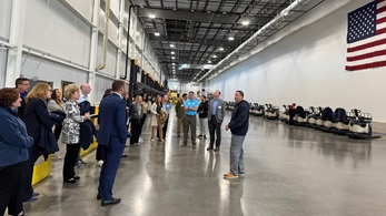 Large distribution center with 30 people listening to a Wegmans employee speak