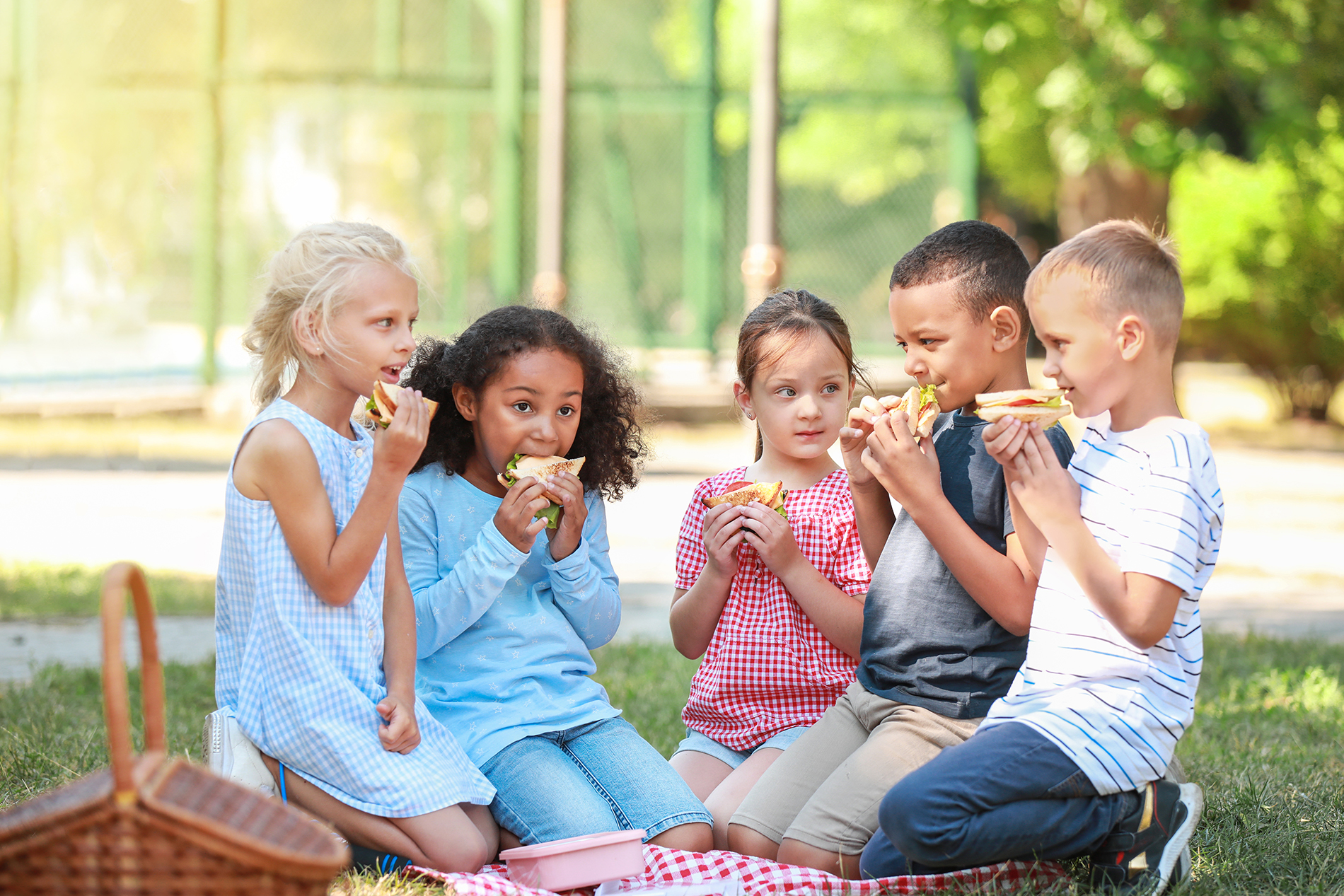 Children eating sandwiches at an outdoor picnic