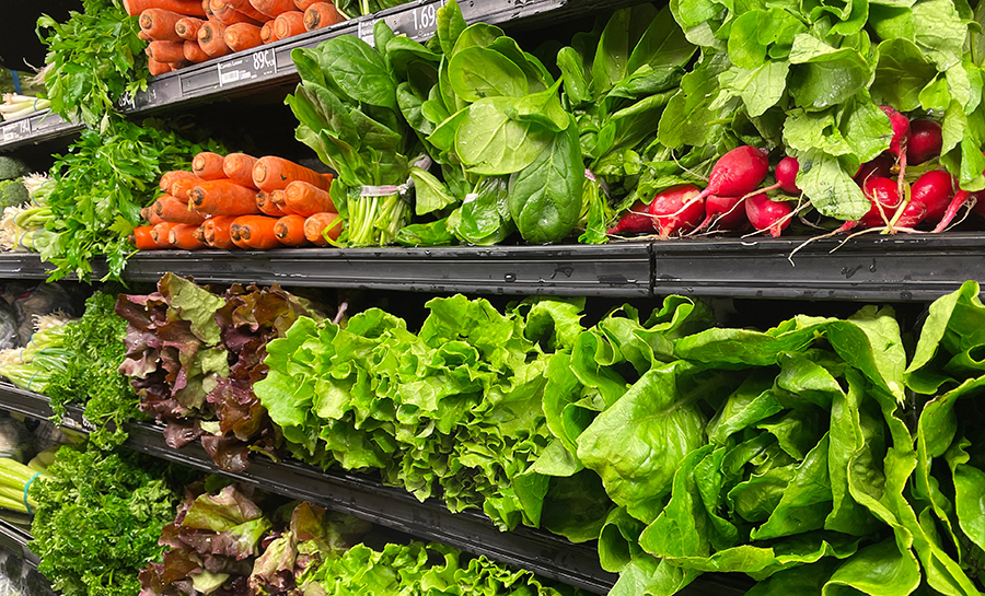Produce in grocery store with lettuce, carrots and radishes.