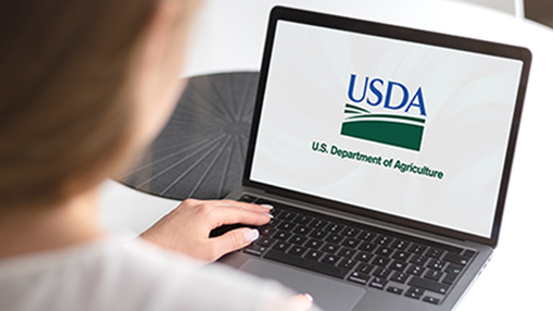USDA logo on a laptop with woman typing