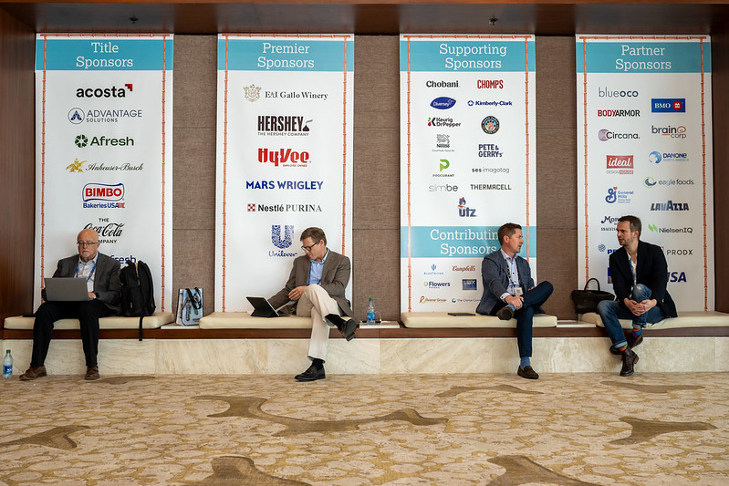 Midwinter guests sitting in front of sponsor banners.